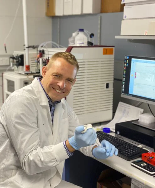  A man in a lab coat with a test tube. 