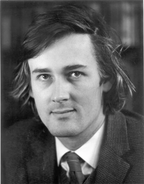 Black and white image of a young man in a tie and jacket. 
