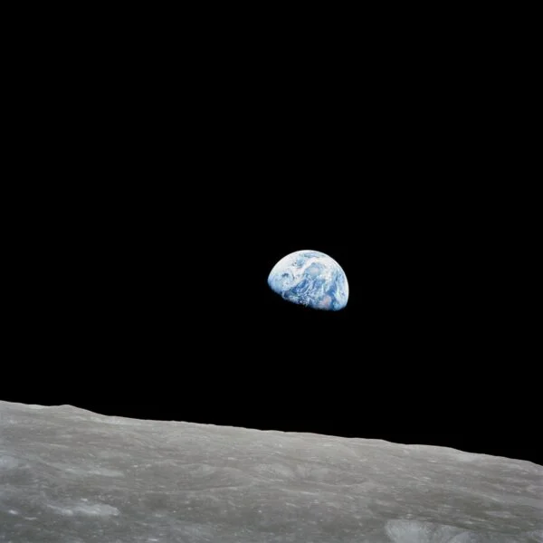 Half of planet earth seemingly floating in space with the grey moon surface below. 