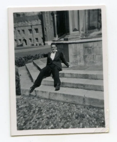 black and white photo of man sat on steps. 