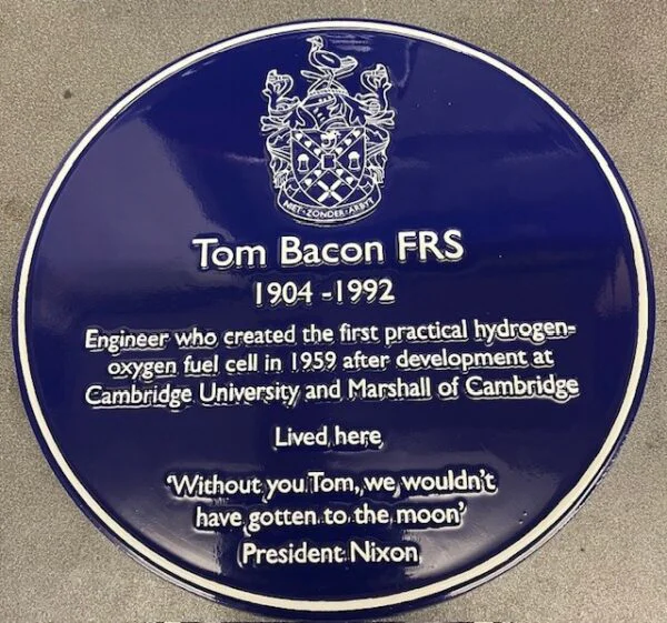 A blue ceramic plaque commemorating Tom Bacon. 