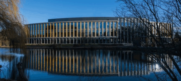 A modern low-rise building beside a lake. 
